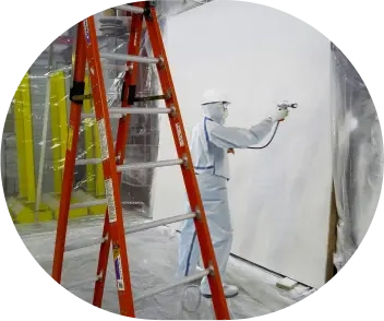 An applicator is spaying intumescent paint on gypsum