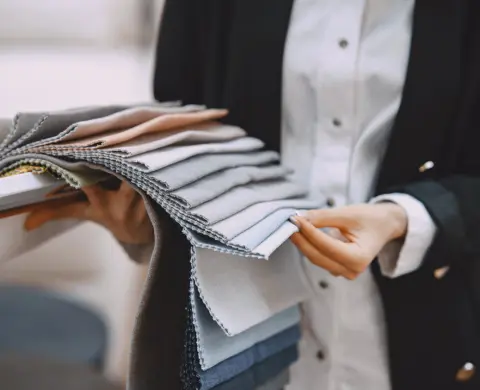 Person holding a fan of fabric swatches while reviewing textiles for fire retardant treatment