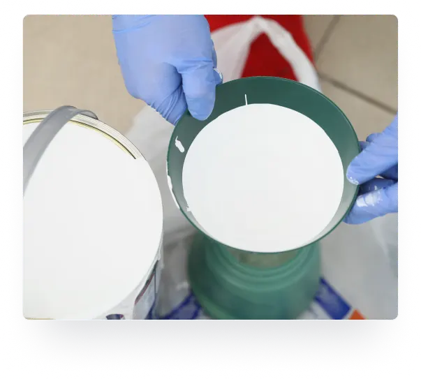Gloved hands mixing white FlameOFF fire retardant coating in a container
